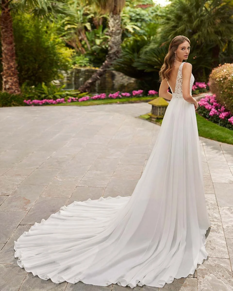 Sposa vista di schiena con abito dalla linea scivolata e coda distesa in giardino