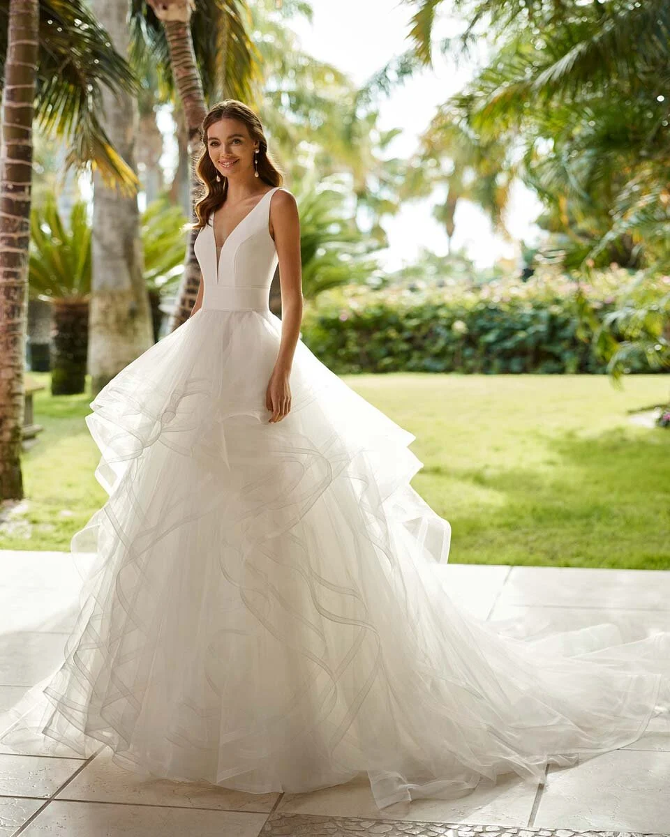 Sposa a figura intera con abito dalla gonna ampia in un giardino