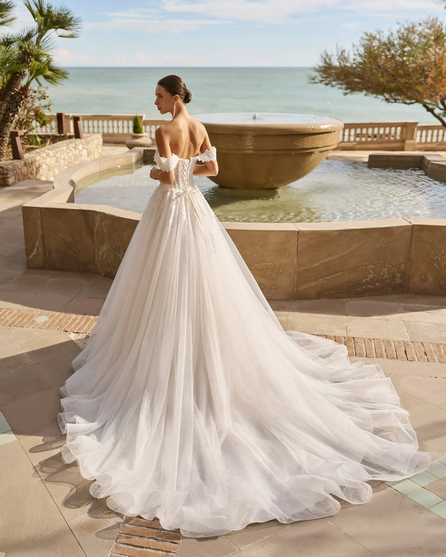 Abito da sposa con gonna ampia e coda distesa su una terrazza